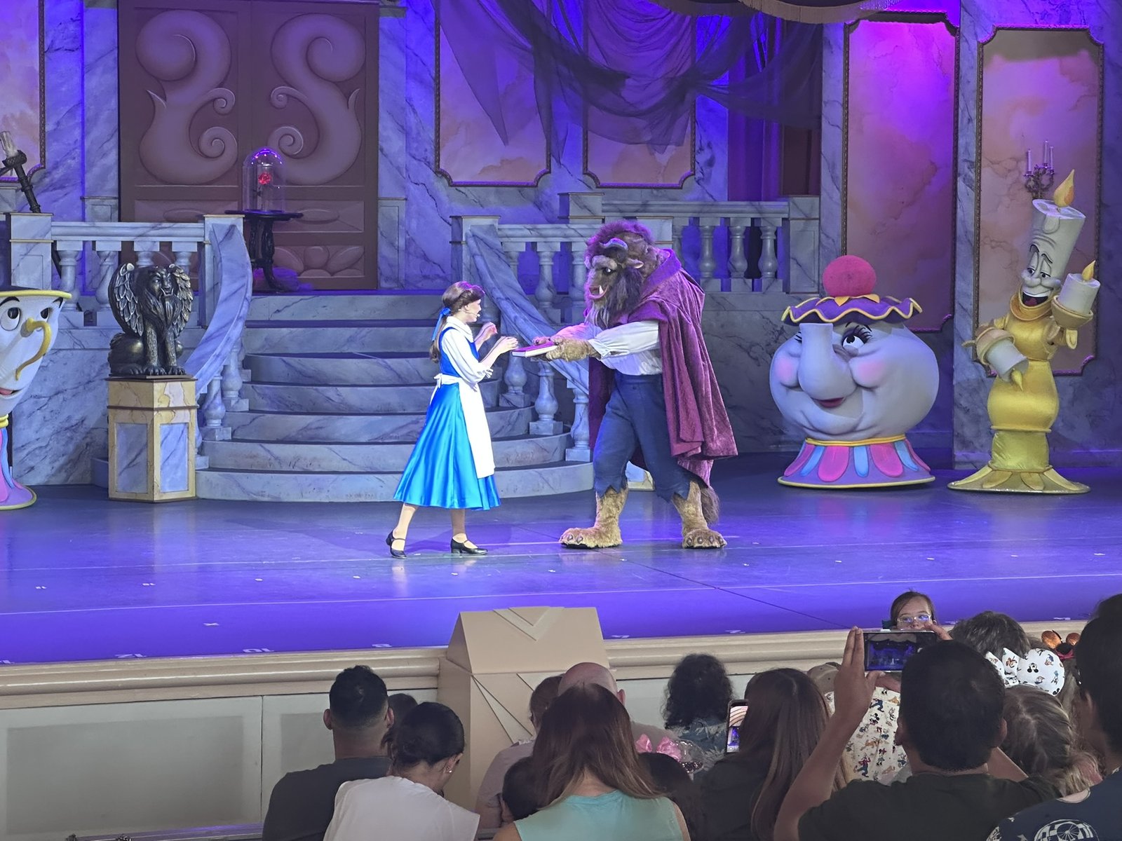 Belle and the Beast on stage with Mrs. Potts, Chip, and Lumière