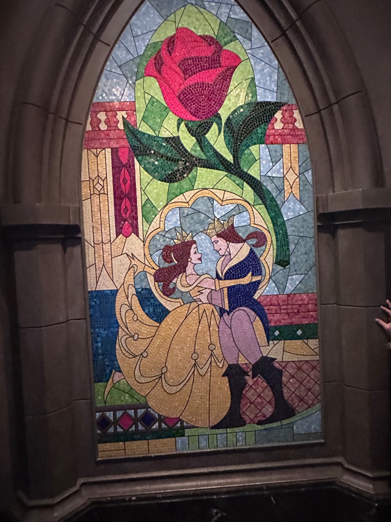 Stained glass of Belle and the Beast under a rose