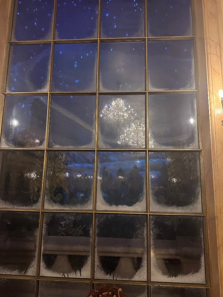 Enchanted window with falling snow inside Be Our Guest