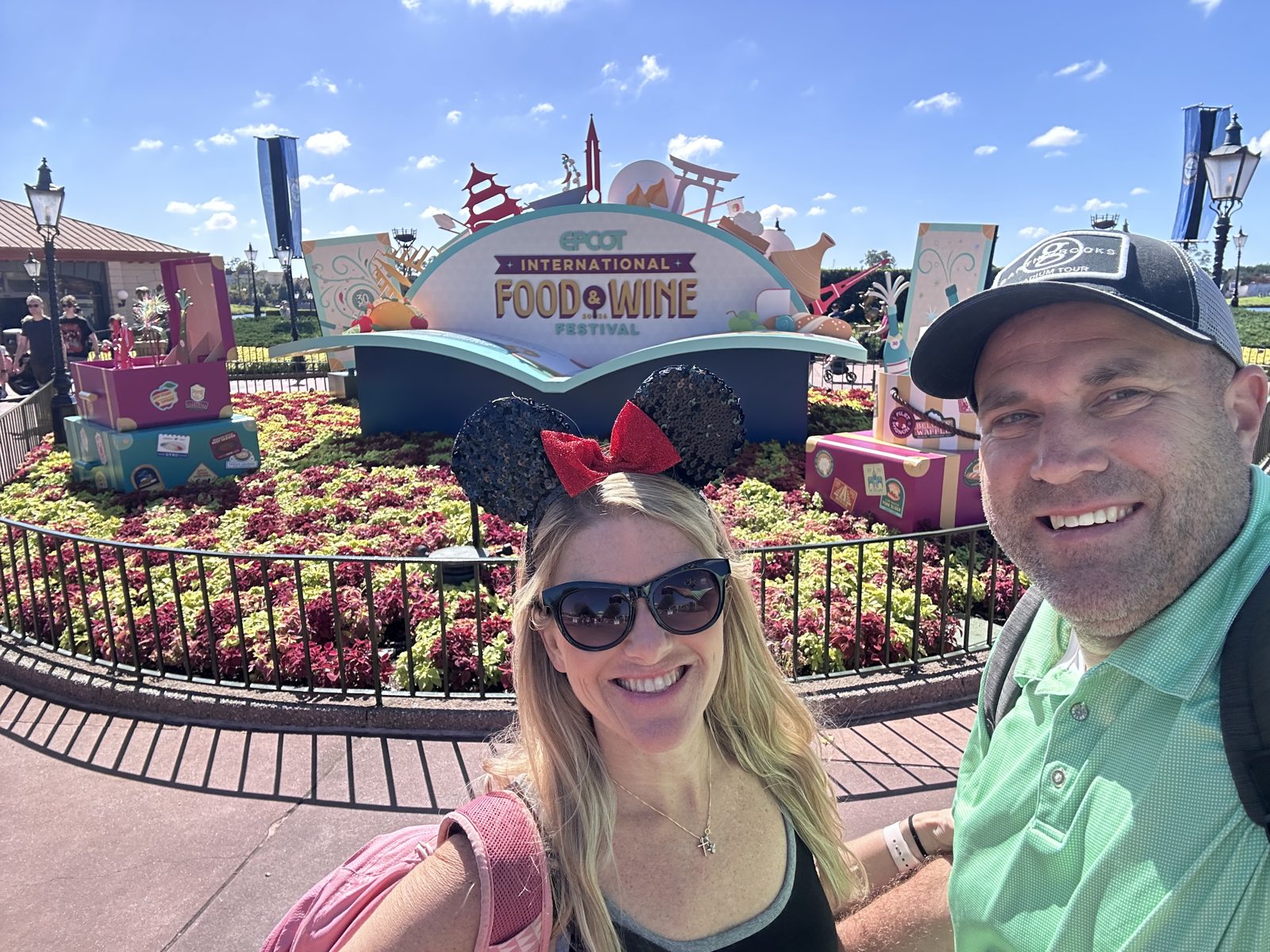 Ryan and Sarah in front of the EPCOT International Food & Wine Festival sign and flower beds