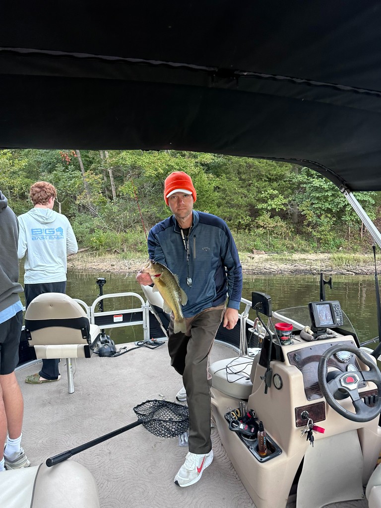 Joel holding a bass on the pontoon