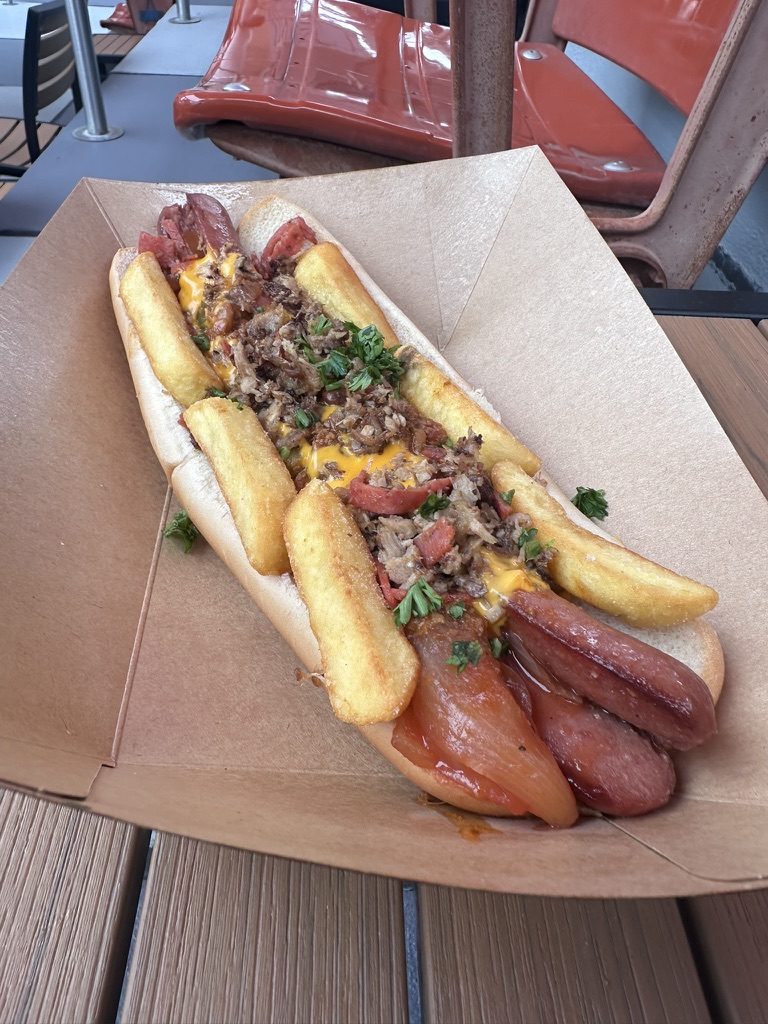The Fat One footlong hot dog with roasted pork, pepperoni, cheese sauce and fries in a paper boat at Fat One's