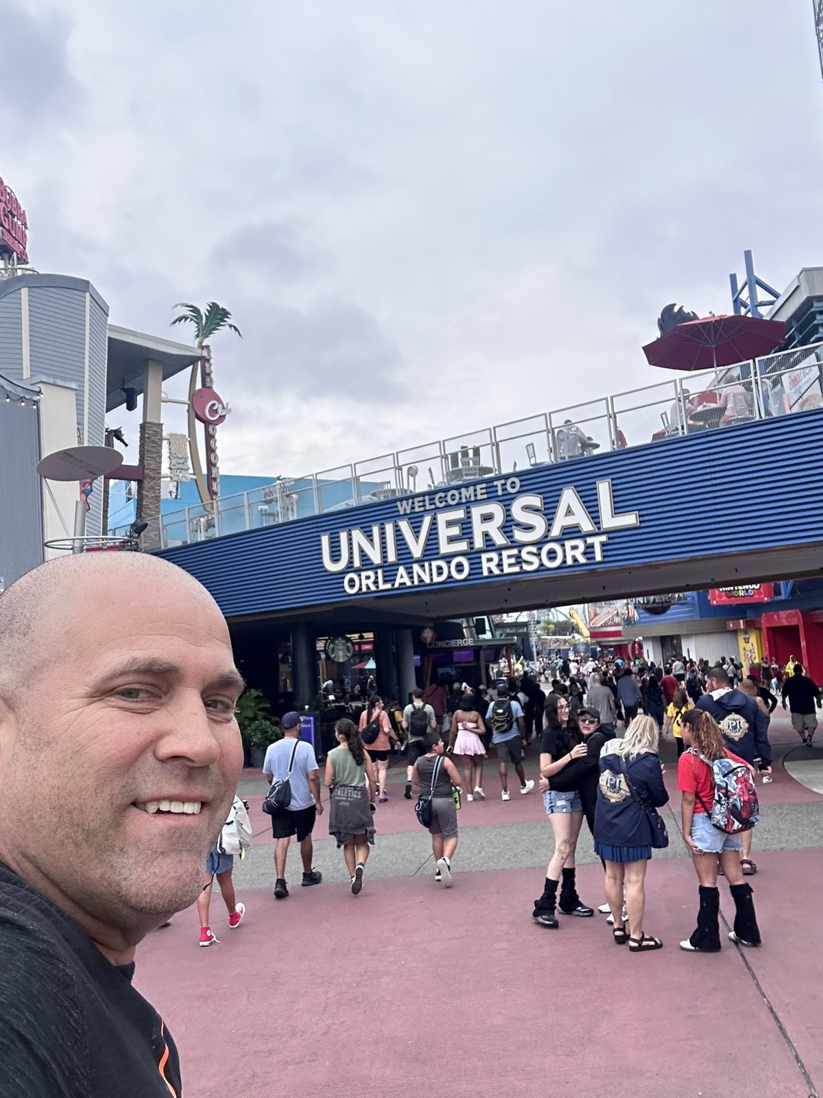 Ryan taking a selfie under the Welcome to Universal Orlando Resort arch into CityWalk