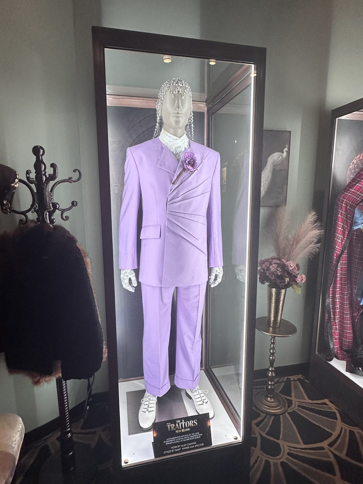 Lavender suit worn by host Alan Cumming in a lit display case