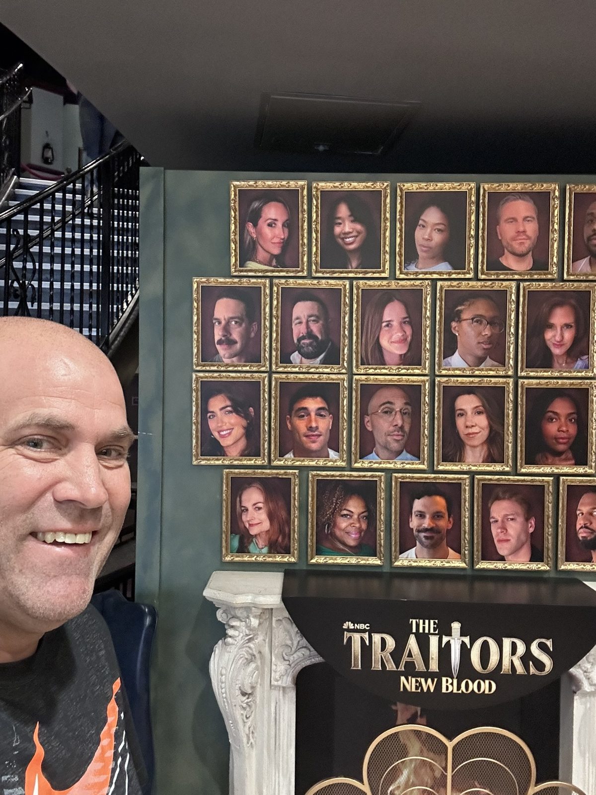 Ryan taking a selfie at the framed cast portrait wall for The Traitors: New Blood